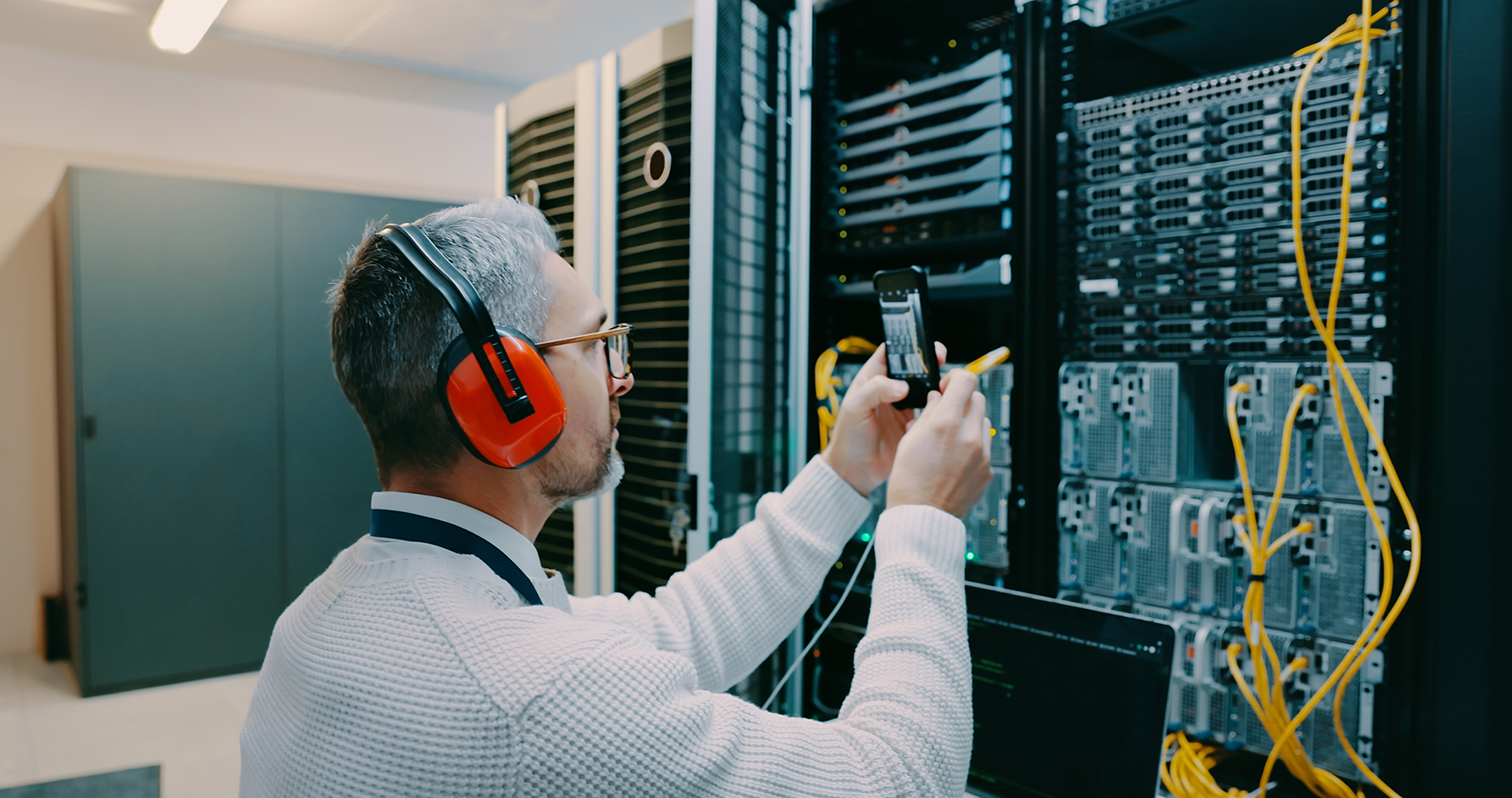 Shot of a male technician using his smartphone to take a photo in a server room